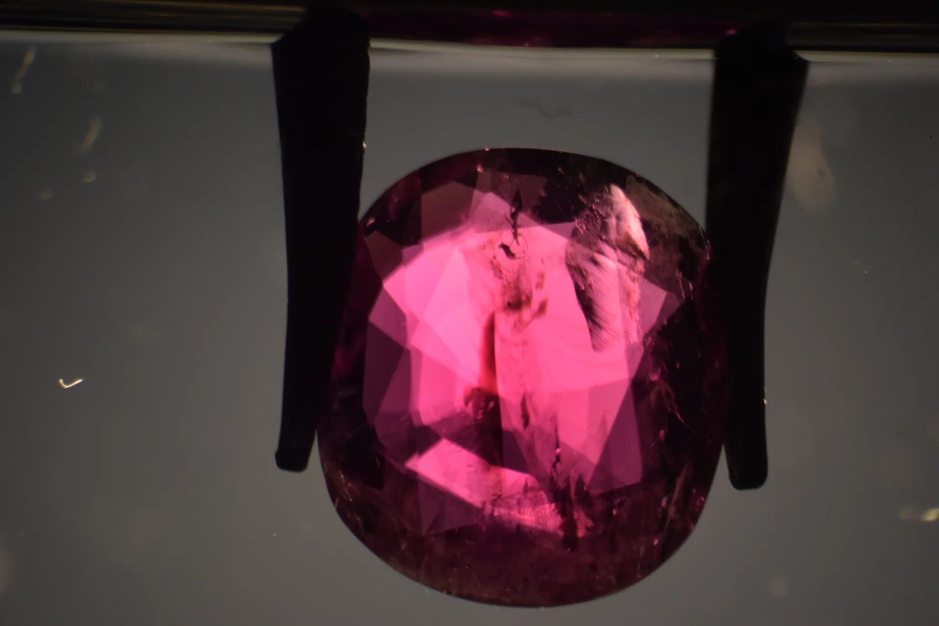 Rosa-violetter Korund, Immersionsmikroskopie: zentrale dunkle Rissfläche, rechts flach liegende reflektierende Spaltfläche