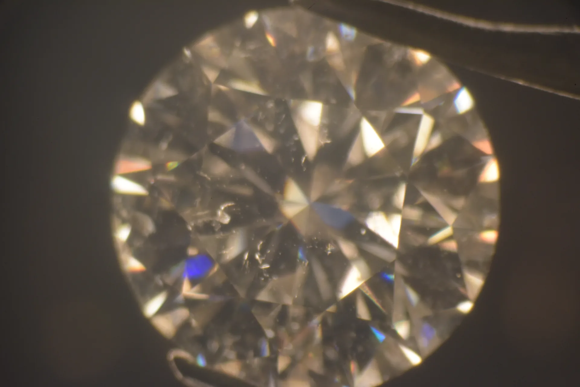 Diamant im Brillantschliff von oben, Dunkelfeld: kleine Kristalle und Federn unter der Tafel, Dispersionsreflexe