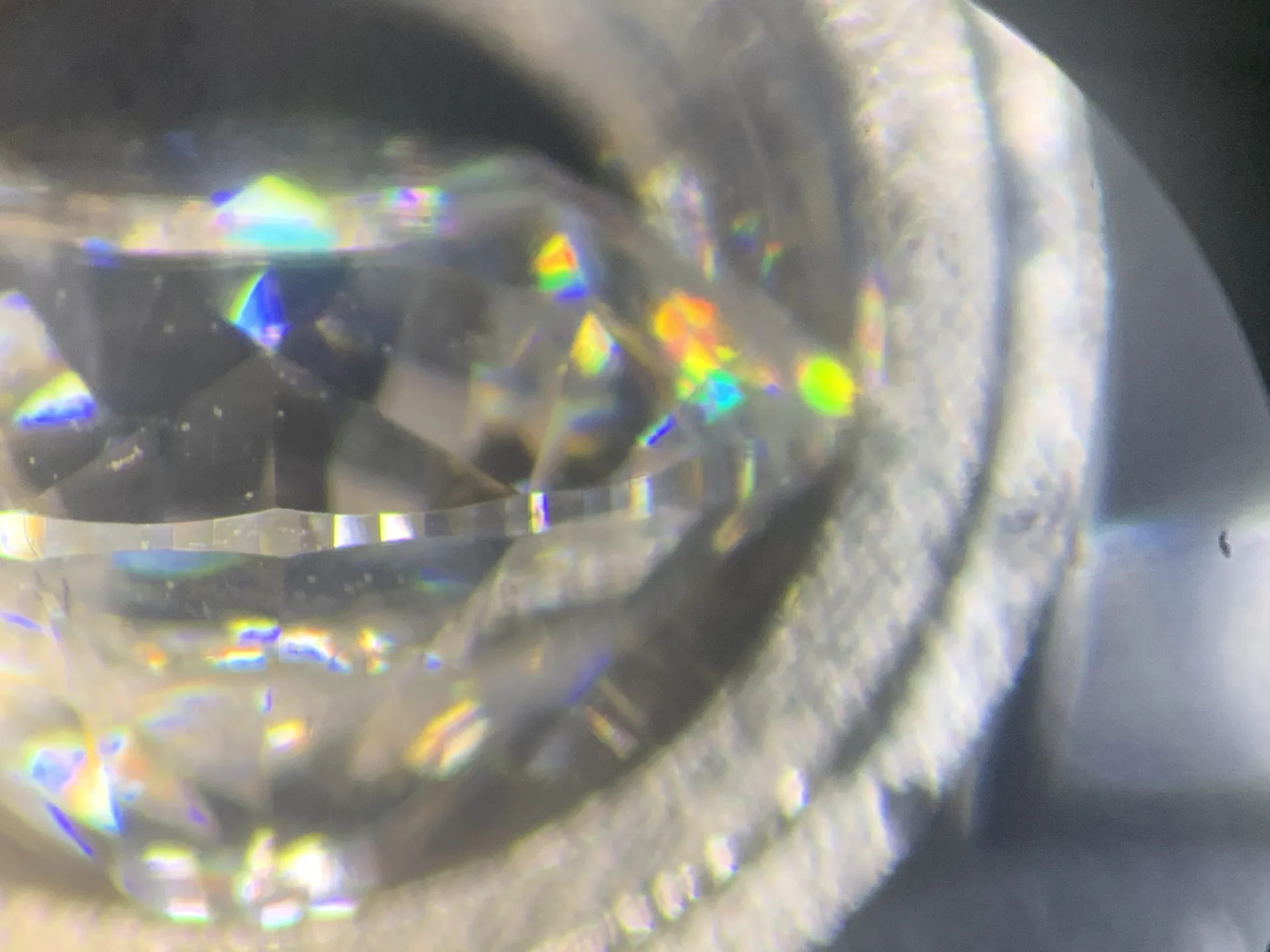 Diamant im Brillantschliff in der Pinzette, Blick durchs Mikroskopokular